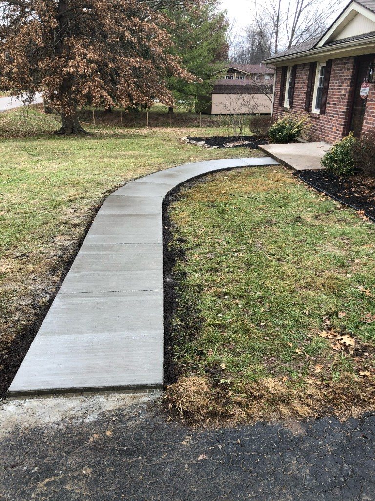 Curved concrete sidewalk from driveway to brick porch