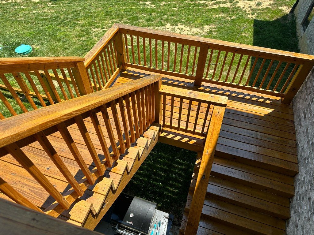 Stained wood deck stairs with landings on a brick home