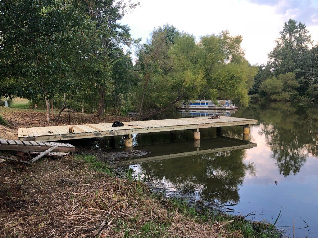 Long wooden dock under construction on a pond