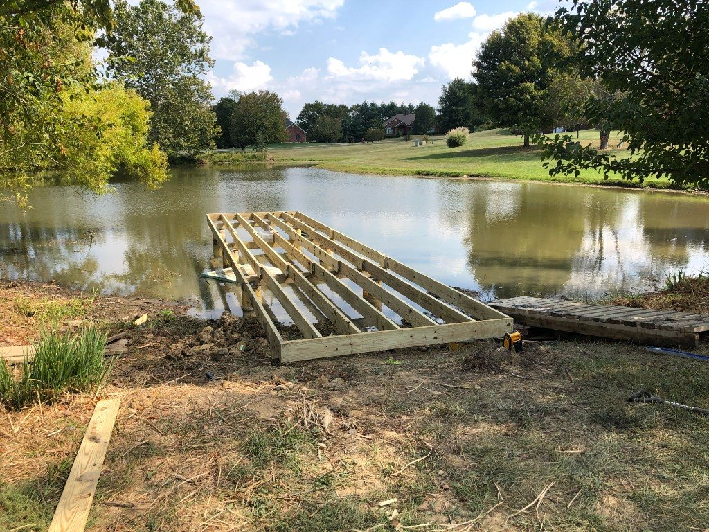 Dock frame joists extending from shore over a pond