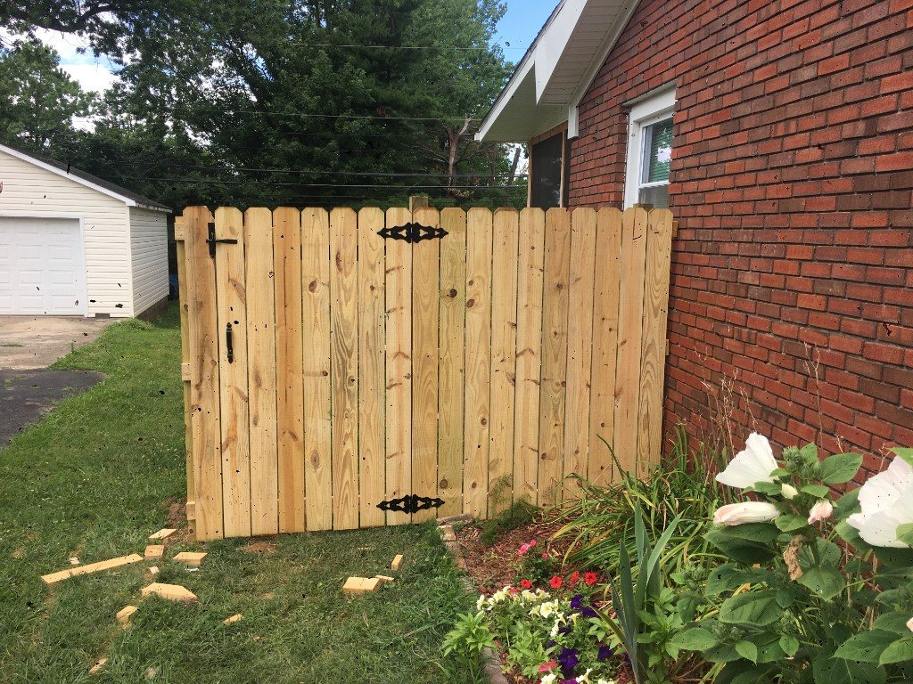 Wooden double gate with black hardware on a brick home