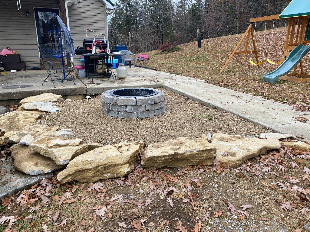 Circular stone fire pit with gravel surround and natural stone border