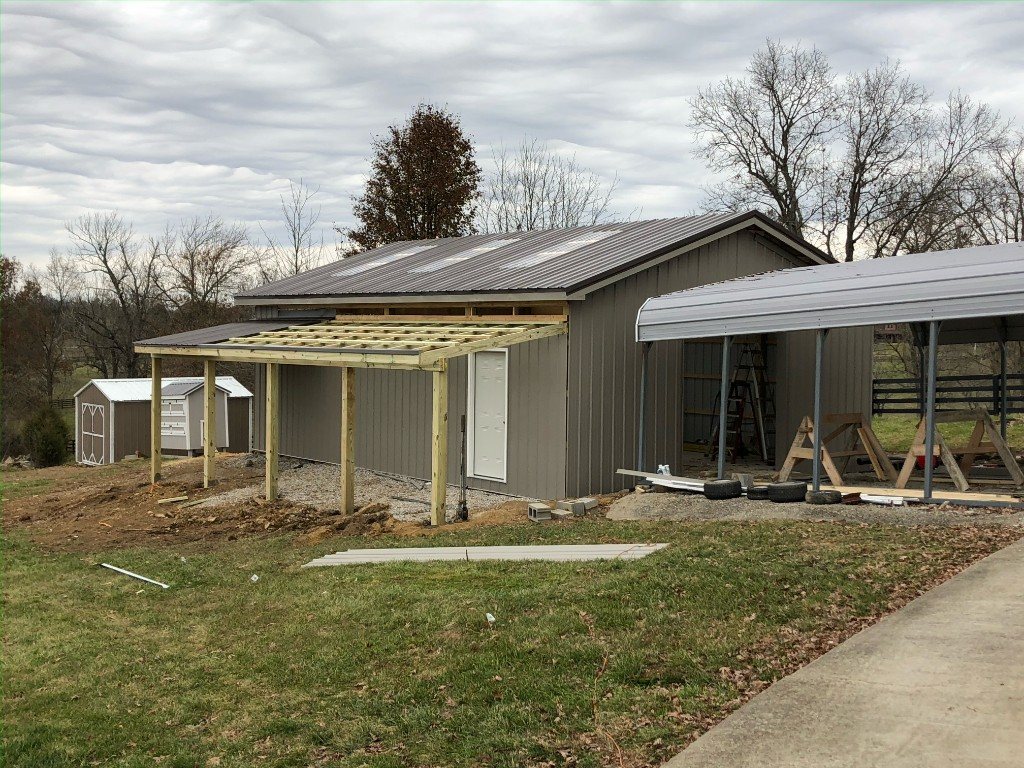 Wooden lean-to frame attached to a metal building before roofing