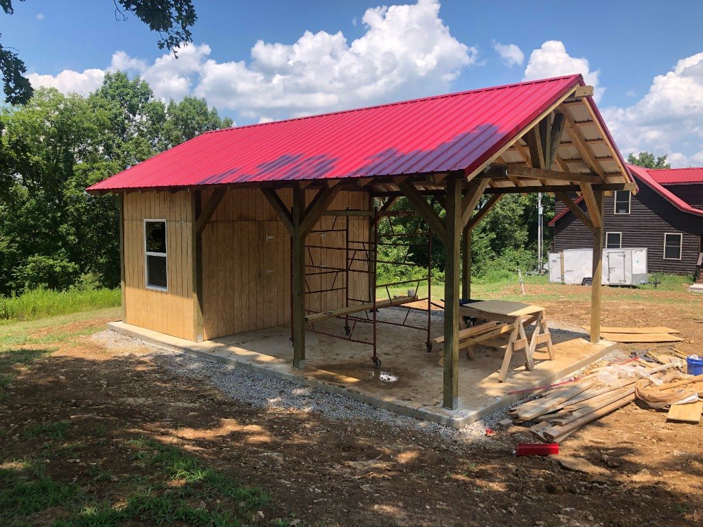 Large wooden pavilion with red metal roof under construction
