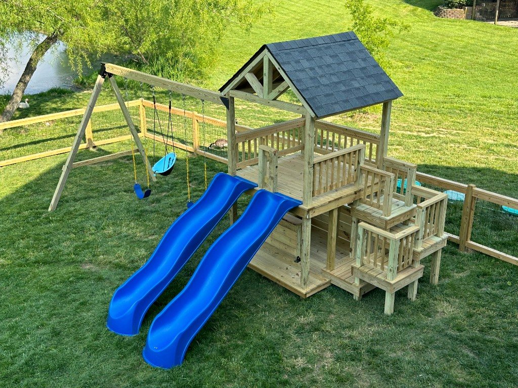 Finished custom wooden playset with two blue slides and swings