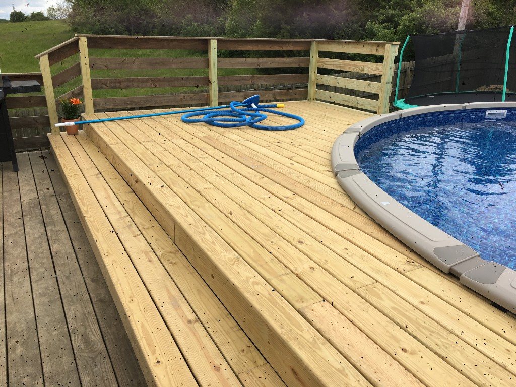 Multi-level wooden deck wrapping an above-ground pool with horizontal rail boards