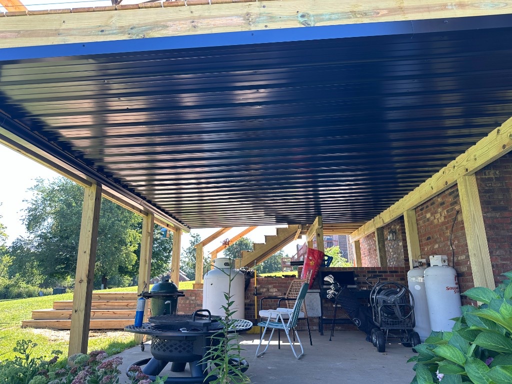 Under-deck drainage system with a finished ceiling and dry patio space below an elevated deck